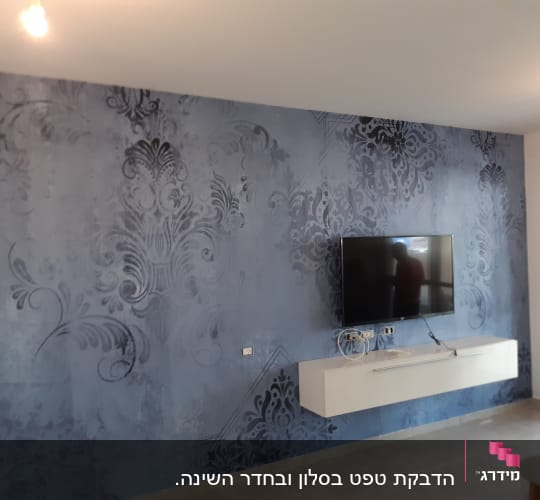קיר כחול עם דוגמאות דקורטיביות וטלוויזיה תלויה